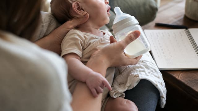 Caregiver supporting an infant with poor feeding and reduced head control, two early warning signs that may occur in infant botulism.